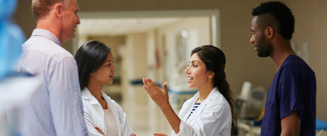 Group of physicians discussing their work in the hallways of a hospital.