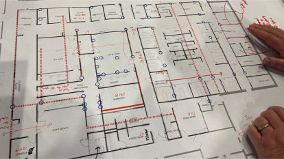 A layout of the current cath lab with red markings and dots over areas to improve.