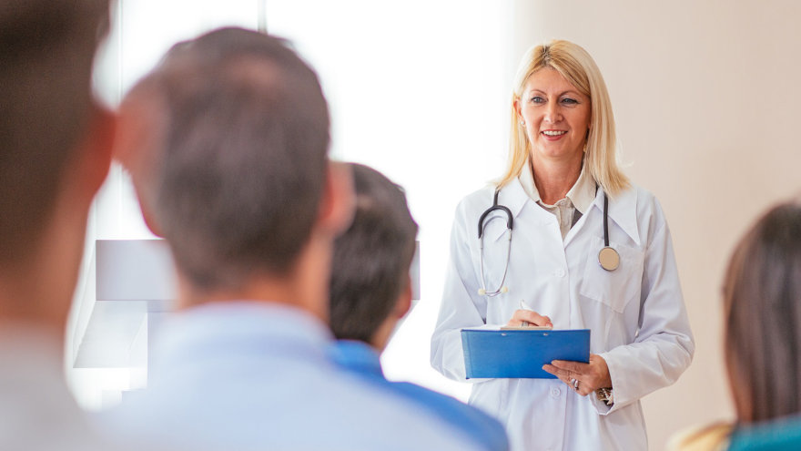 A doctor presenting in front of a crowd of people.