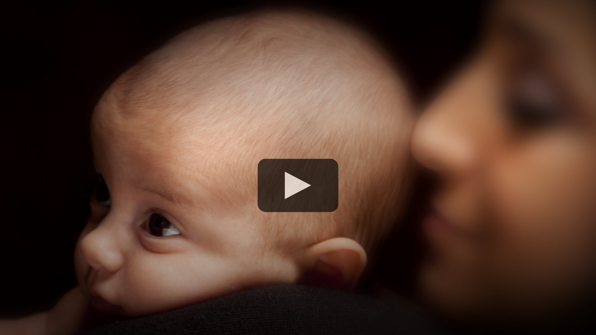 A woman holding her newborn baby close.